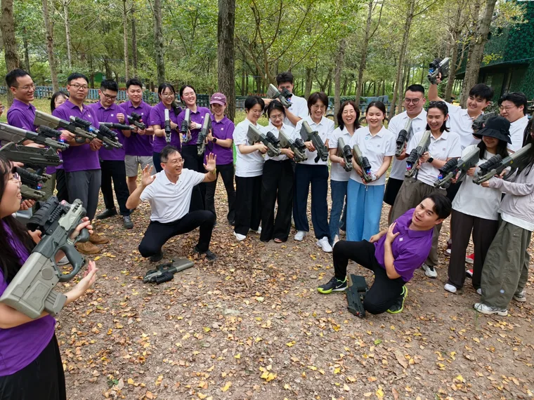 Colleagues facing off with laser-tag guns, two kneeling in front making dramatic faces